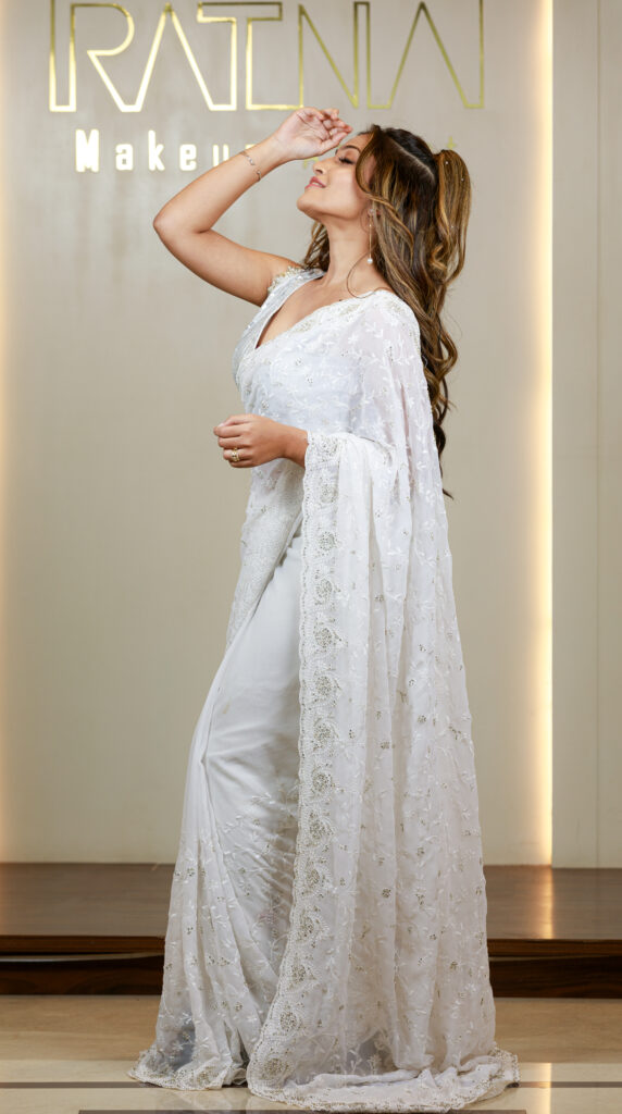 South Indian bride posing elegantly in a white saree with detailed embroidery, showcasing a modern reception look.